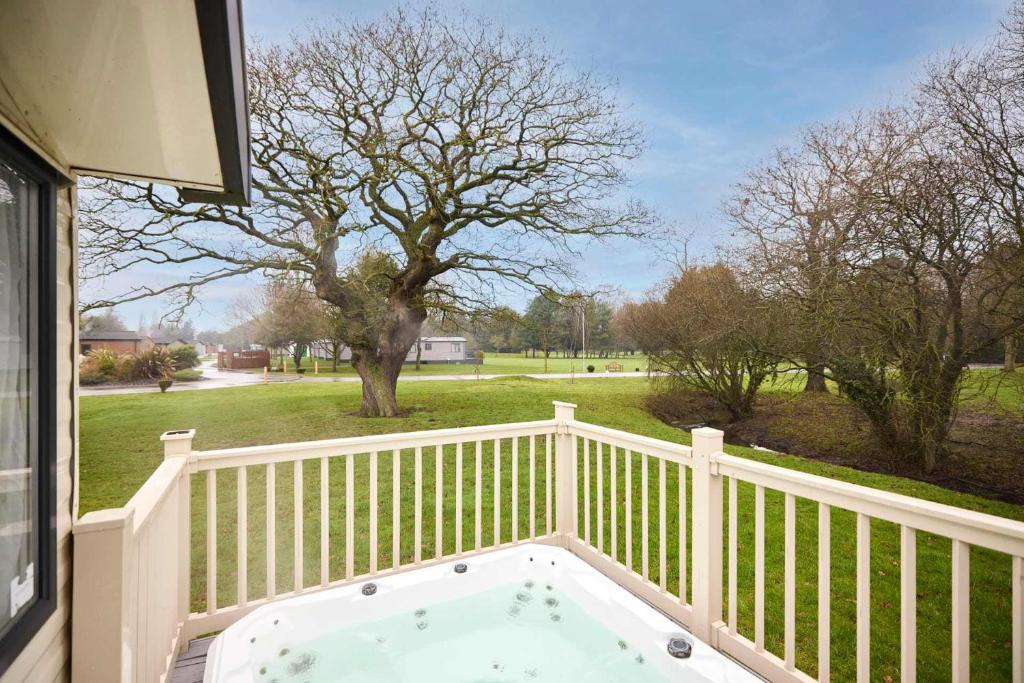 a hot tub on a porch with a fence at The Major Oak Lodge with Hot Tub in York
