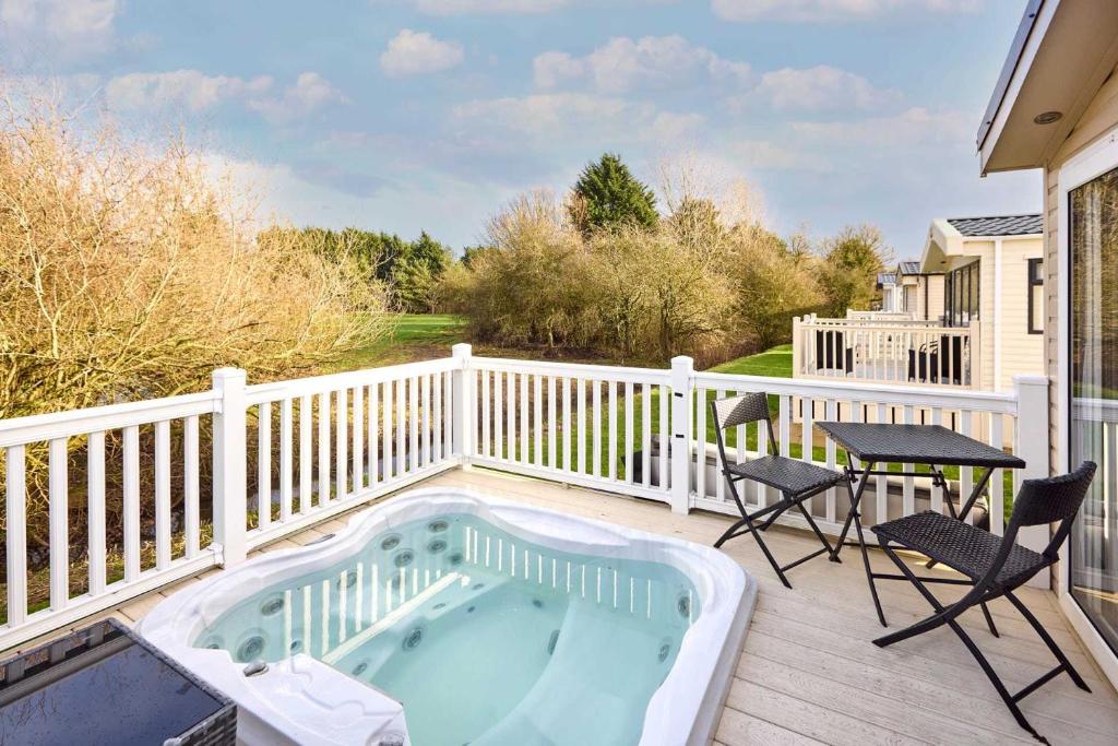 a hot tub on a deck with a table and chairs at Cedar Lodge With Hot Tub in Pocklington