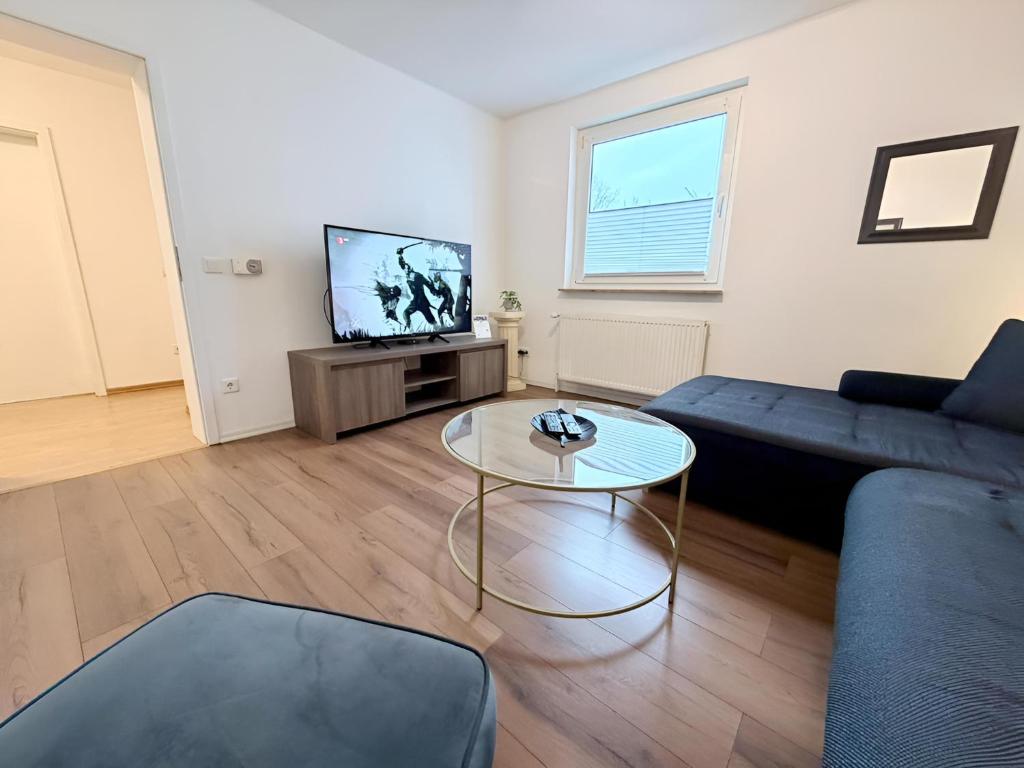 a living room with a couch and a table and a tv at FeWo Lindenallee Modern & Ruhig in Nordhorn
