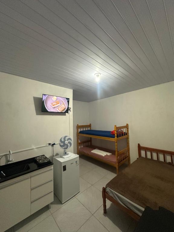 a room with a bedroom with a bed and a kitchen at NOVO Ap Econômico em Paranaguá Completo com WiFi e Estacionamento Rotativo in Paranaguá
