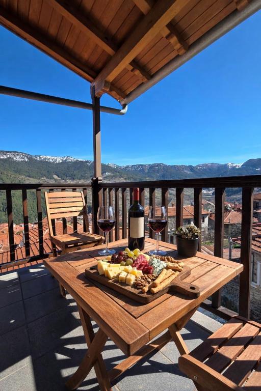 a wooden table with a plate of food and wine at Metsovo Fireplace Retreat 2 in Metsovo