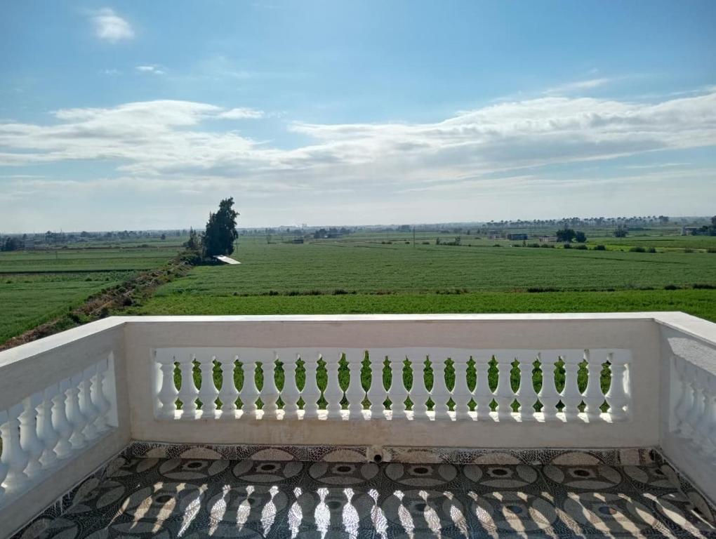 a white balcony with a view of a green field at Marwan Farmhouse Rooftop Apartment in Faraj Māḑī