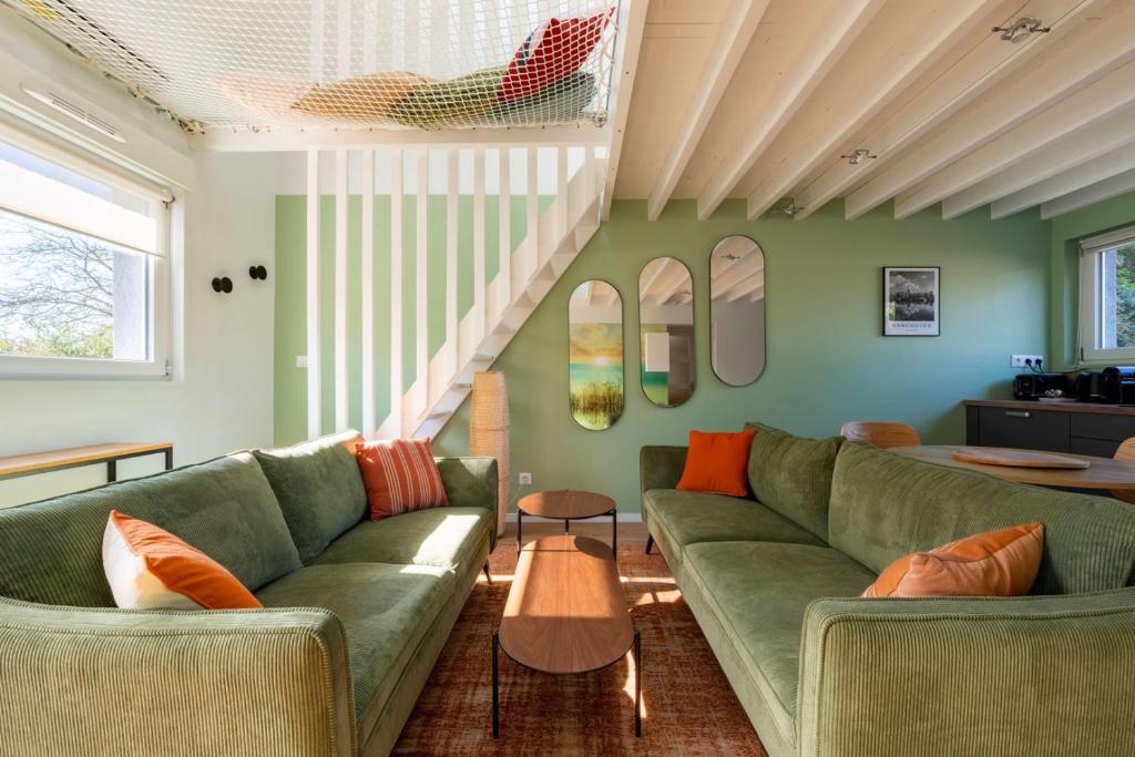 a living room with a green couch and a table at Air Nomad • Vancouver in Valenciennes