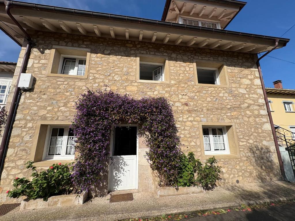 a stone house with purple ivy on the facade at La Casa de Nueva in Nueva de Llanes