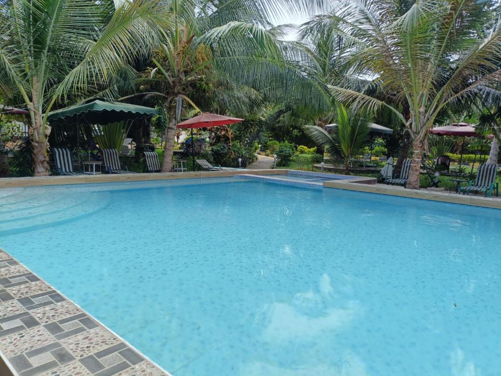 a large blue swimming pool with palm trees at Escape Retreats in Diani Beach