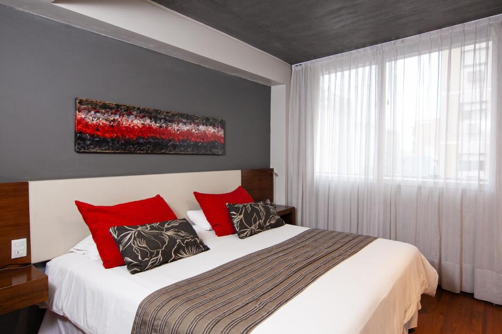 a bedroom with a large bed with red pillows at Amérian Tucuman in San Miguel de Tucumán