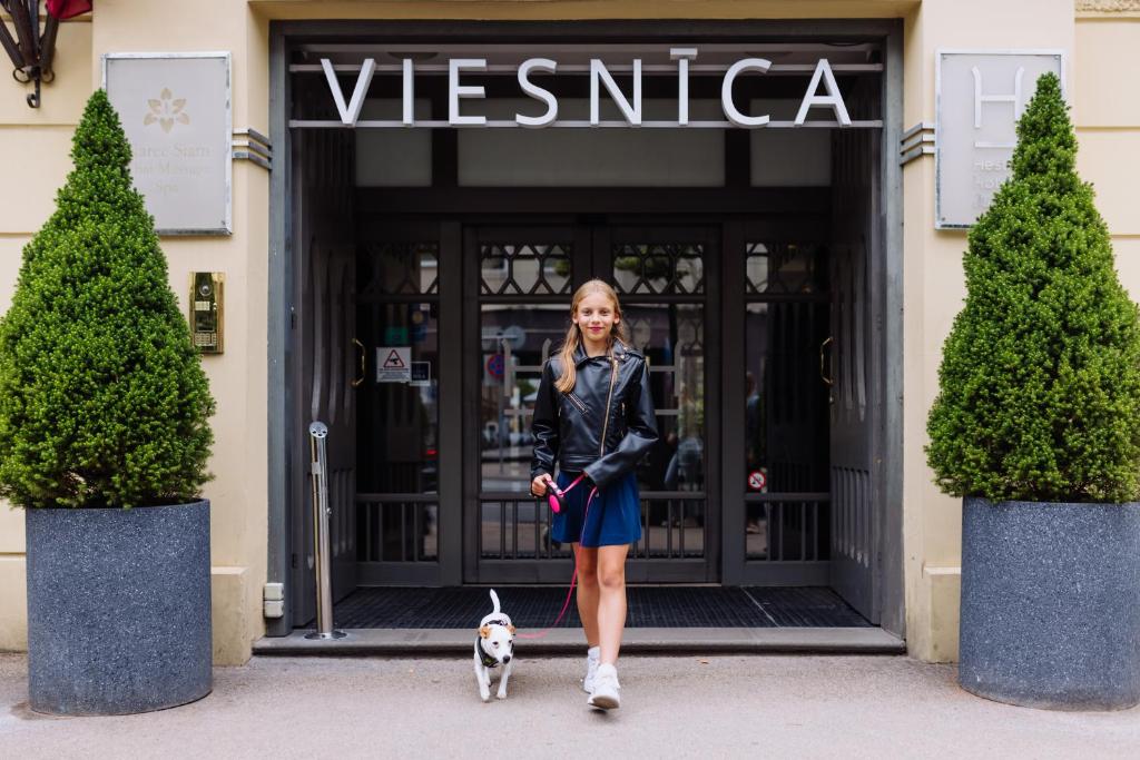 a woman walking a dog in front of a store at Hestia Hotel Jugend in Riga