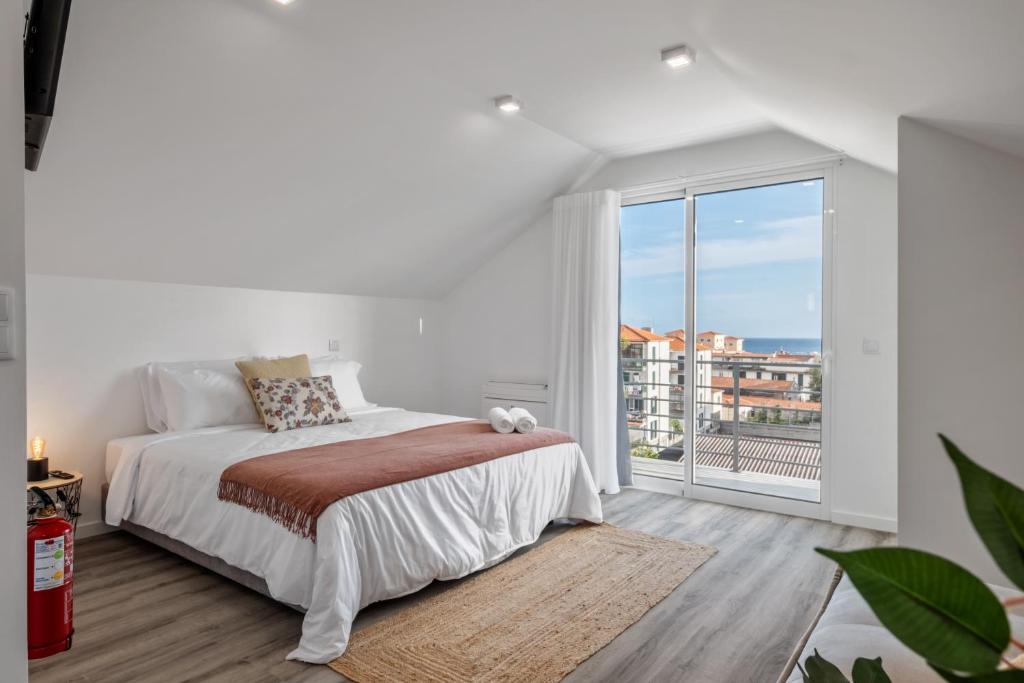 a white bedroom with a bed and a large window at Brito's Guest House - Monthly Rentals & Digital Nomads in Funchal