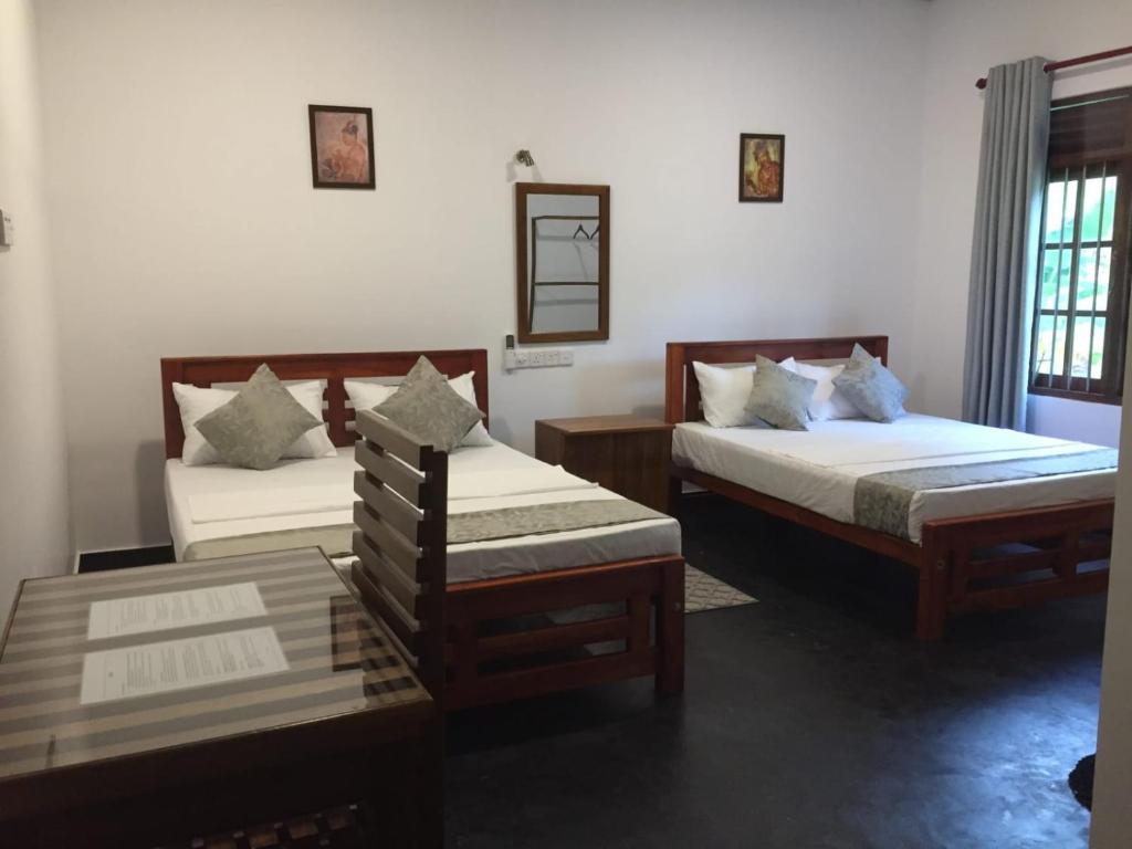 a bedroom with two beds and a table at Mimi's Cottage in Udawalawe