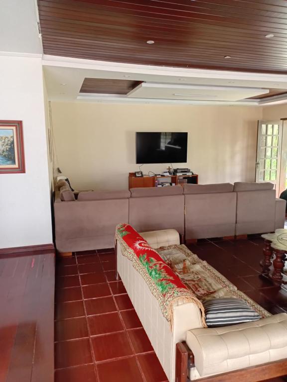 a living room with a couch and a flat screen tv at Casa Compartilhada na CBF, granja comary in Teresópolis