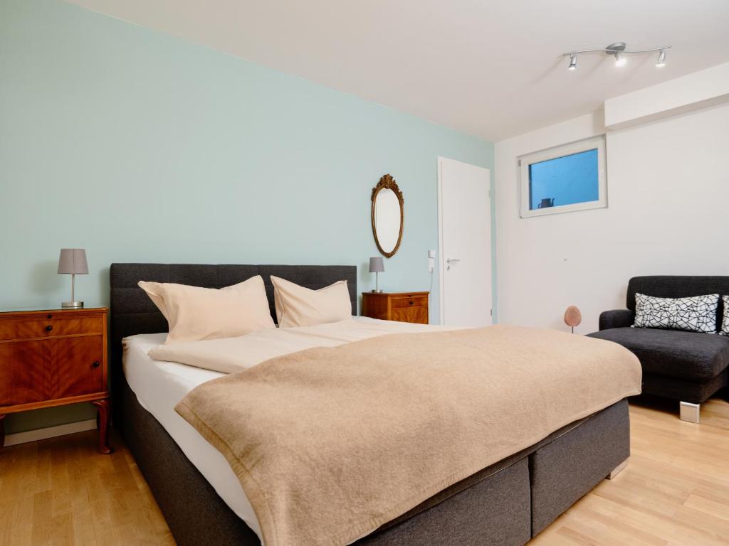 a bedroom with a large bed and a chair at Beim Thöny - schönes Apartment mit privatem Zugang in Utting am Ammersee
