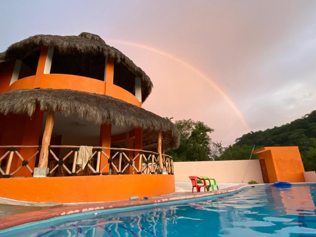 a rainbow over a swimming pool with a hotel at Las Casitas de La Bahia Calechosa in Emiliano Zapata
