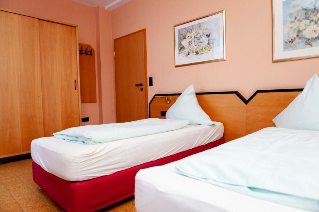 a hotel room with two beds and a red suitcase at Hotel Karger in Wadersloh