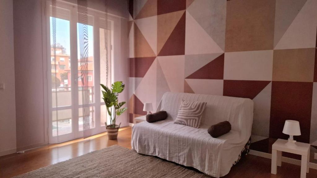 a living room with a white couch and a geometric wall at Casa di Giada - Venice Gateway - Family Comfort - Free Public Parking& Tram -Link in Mestre