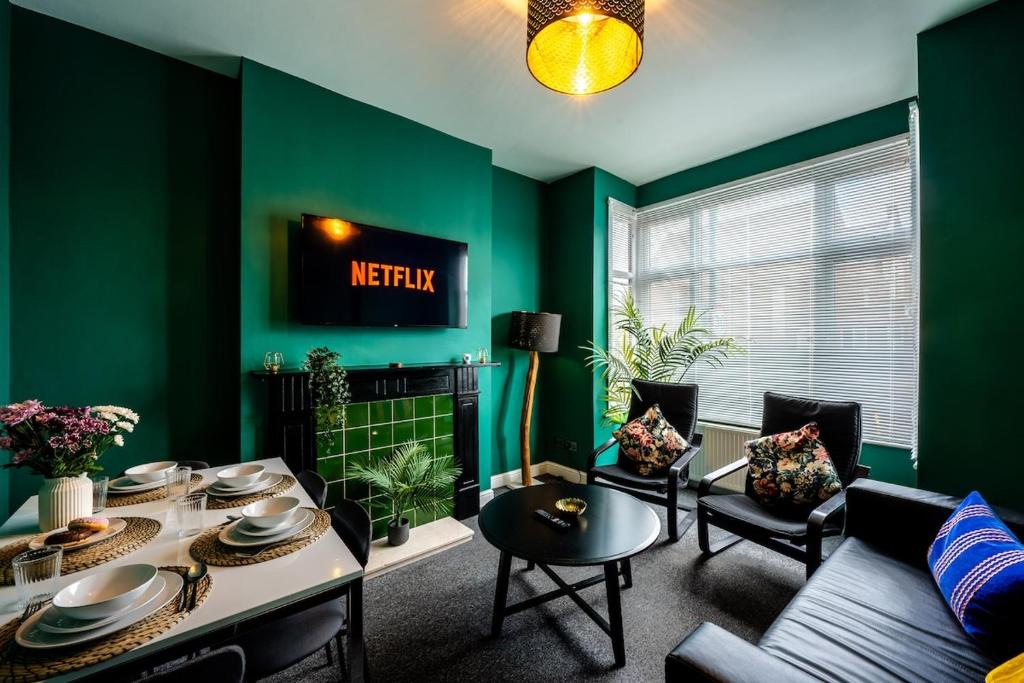 a living room with green walls and a table and chairs at Spacious Central Nottingham House in Nottingham