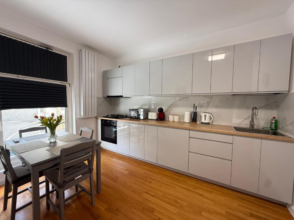 a kitchen with white cabinets and a dining table at Scandinavian AP in Craiova