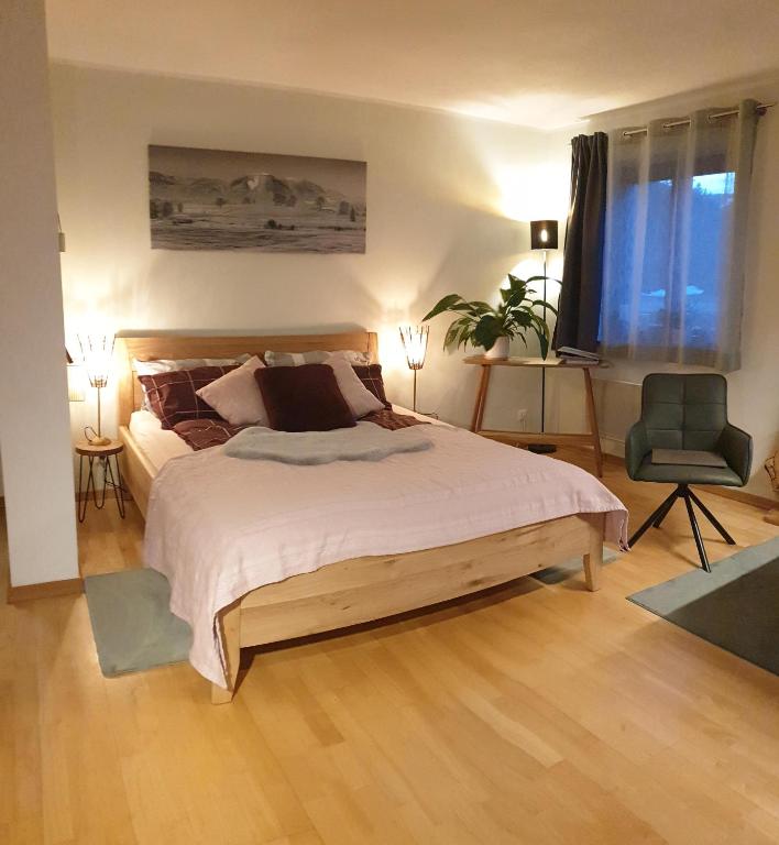 a bedroom with a large bed and a chair at Frisch renoviertes BergSeeNest in Bad Bayersoien