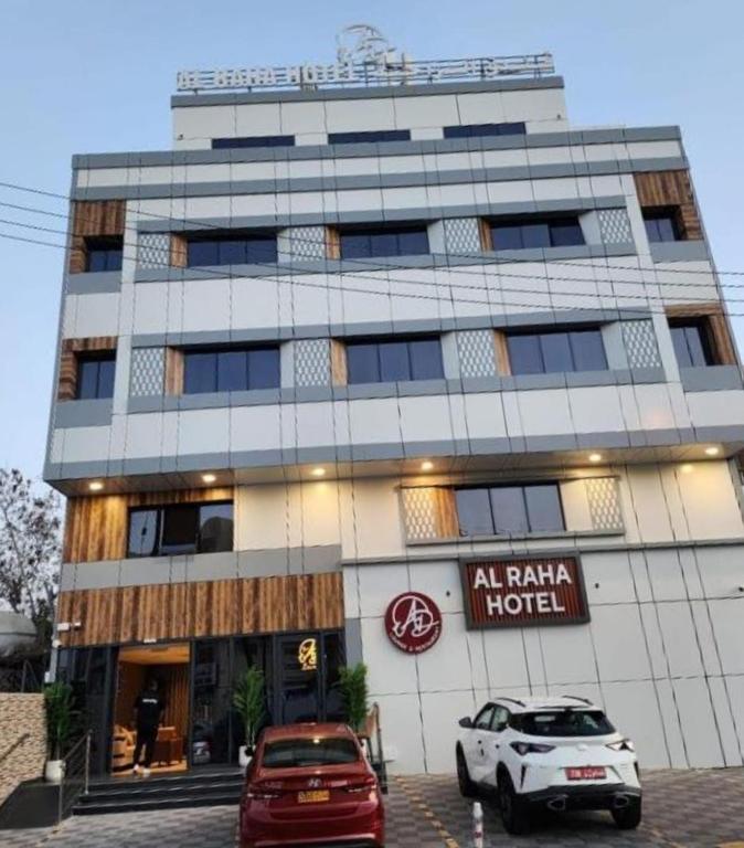 a building with two cars parked in front of it at Al RAHA HOTEL in Muscat