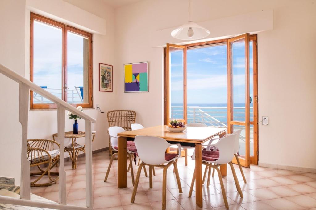 a dining room with a table and chairs and a balcony at Villa Elvira - Apulian Stay Group in Faccia di Trippa