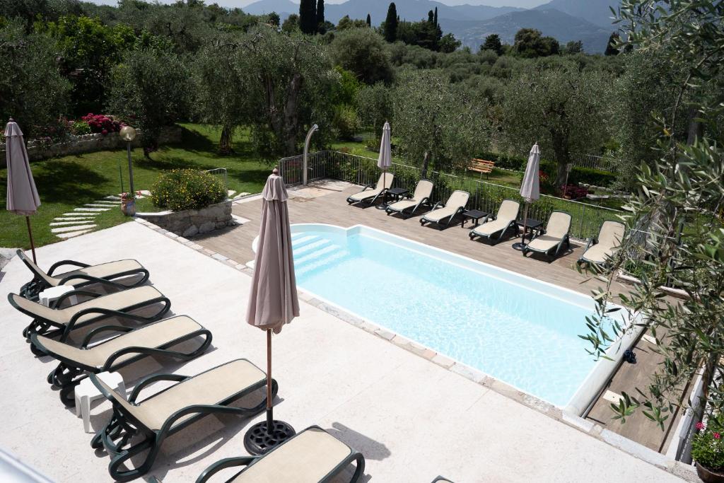 a swimming pool with lounge chairs and umbrellas next to it at appartamenti ceccherini debora luna in Malcesine