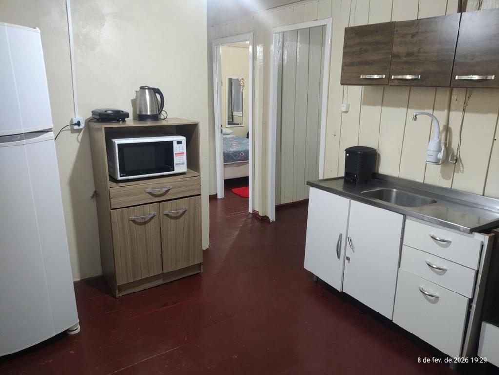 a kitchen with a sink and a microwave on a counter at Casa 2 Quartos - Vila Real in Chapecó