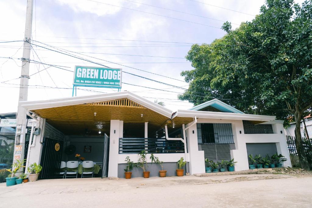 a white building with a green lounge sign on it at Green Lodging House in Anda