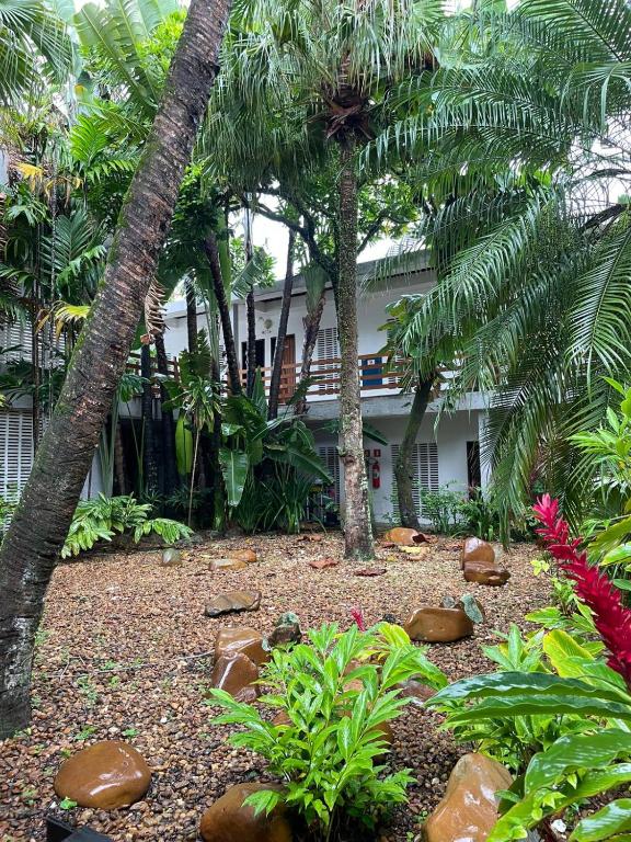 a garden in front of a house with palm trees at Suíte aconchegante beira mar - Suíte 255 in Guarujá