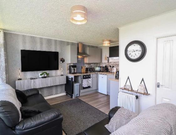 a living room with a couch and a clock on the wall at 106 Cherry park in Chapel Saint Leonards