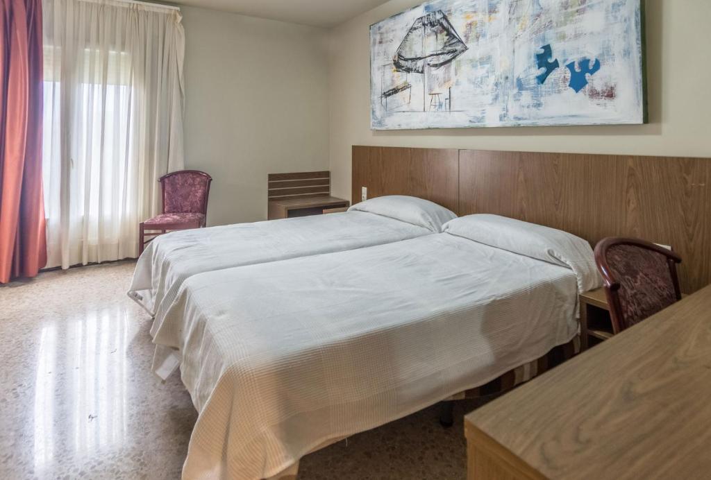 バラゲーにあるHostal Sant Miquelのベッドルーム1室(大型ベッド1台、木製ヘッドボード付)
