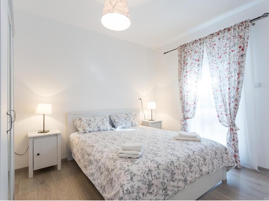 a white bedroom with a bed and a window at Apartments Urban Porec in Poreč