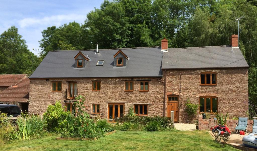 una grande casa in mattoni con tetto grigio di Woodmill Farm Apartment ad Alvington