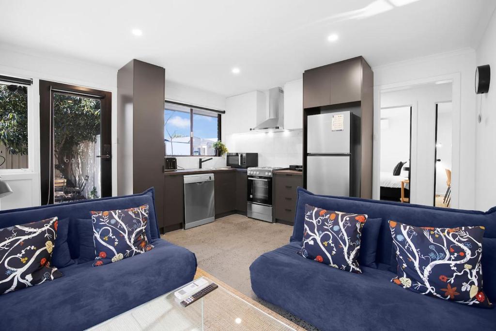 a living room with a blue couch and a kitchen at Sunshine Family Sophistication in Albion