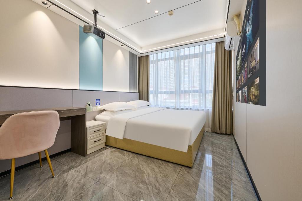 a bedroom with a bed and a desk and a chair at Four Seasons Clouds Xiamen North Railway Station Store in Xiamen