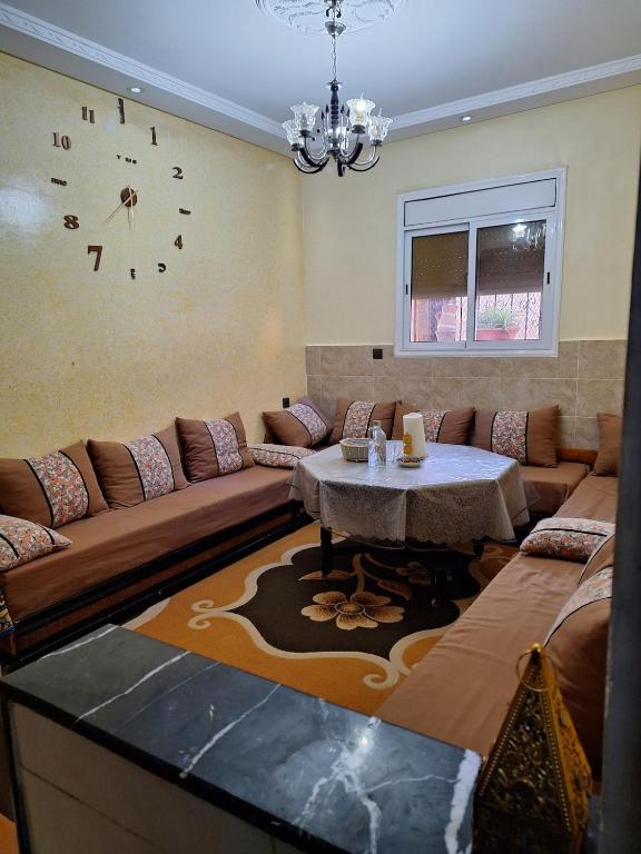 a living room with a couch and a clock on the wall at Nawal's guest house in Tadouart