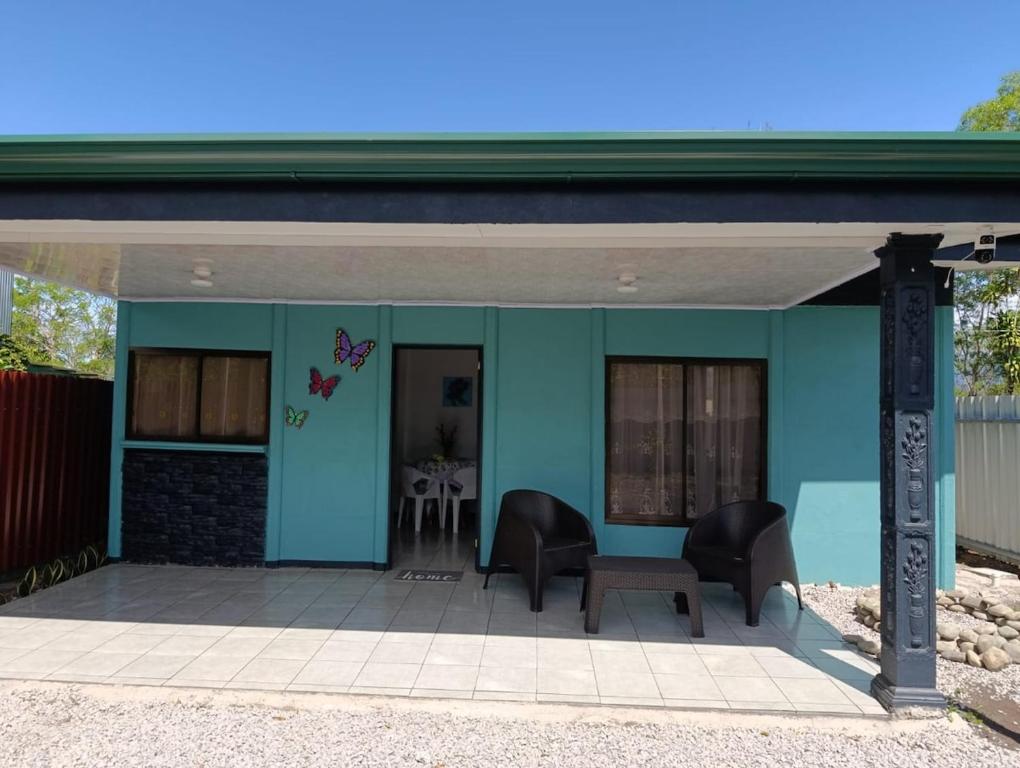 a blue house with two chairs and a table at Casa Mariposa Full Accommodation in Sabalito