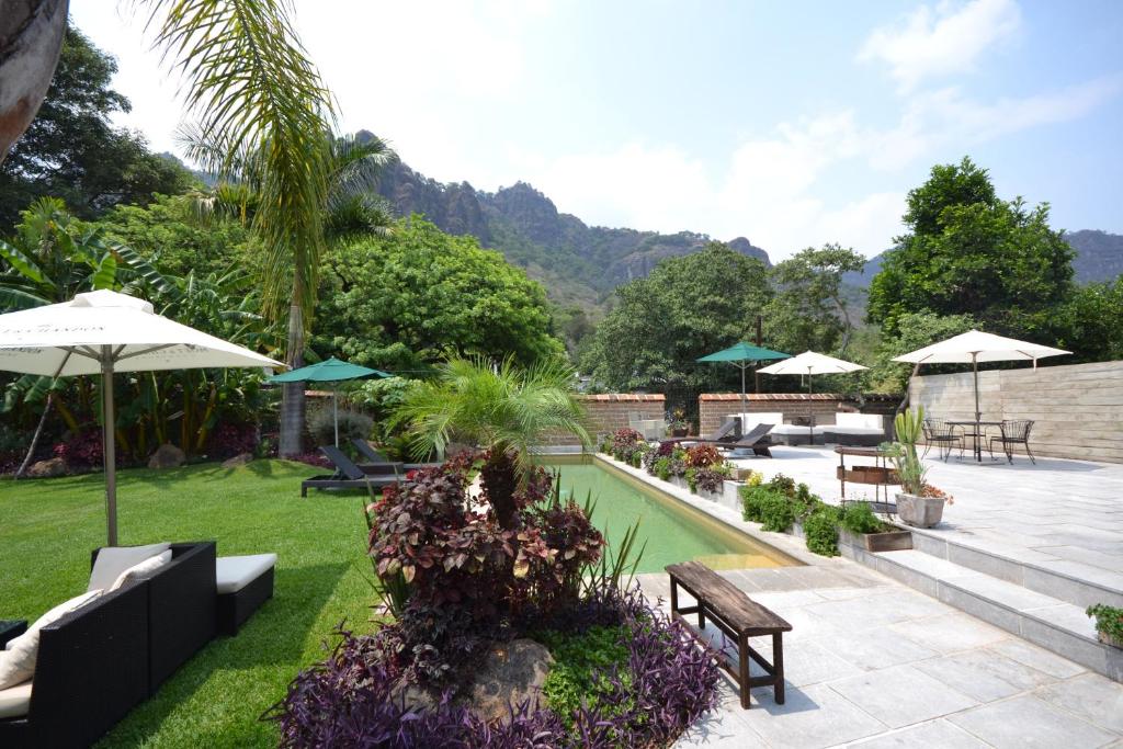 un jardín con bancos y sombrillas y una piscina en Rústika SPA Hotel Boutique, en Tepoztlán