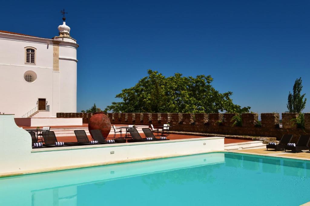 a swimming pool in front of a building with a lighthouse at Pousada Castelo de Estremoz in Estremoz