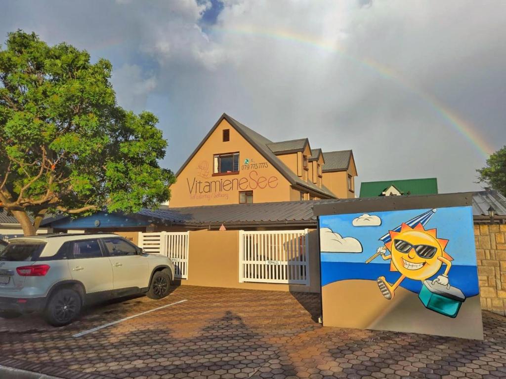 a rainbow over a building with a car parked in front at Vitamiene-See Hartenbos in Hartenbos