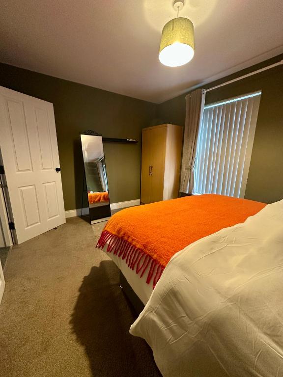 a bedroom with a bed with an orange blanket at Belles Haven in Belfast