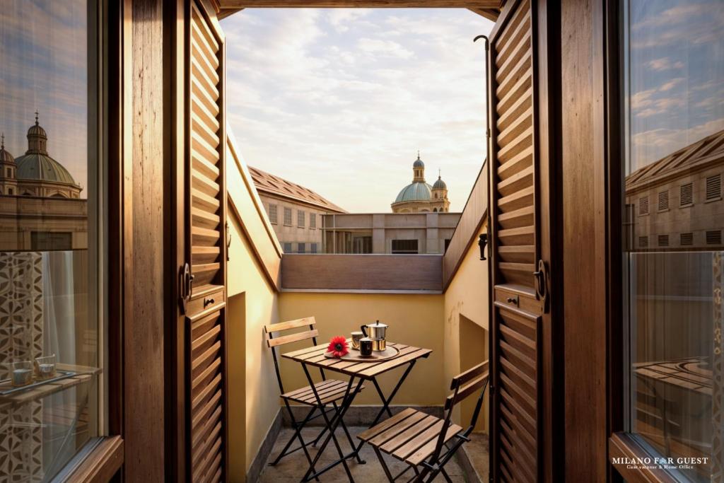 a small table on a balcony with a view of the city at The Central Milano in Milan