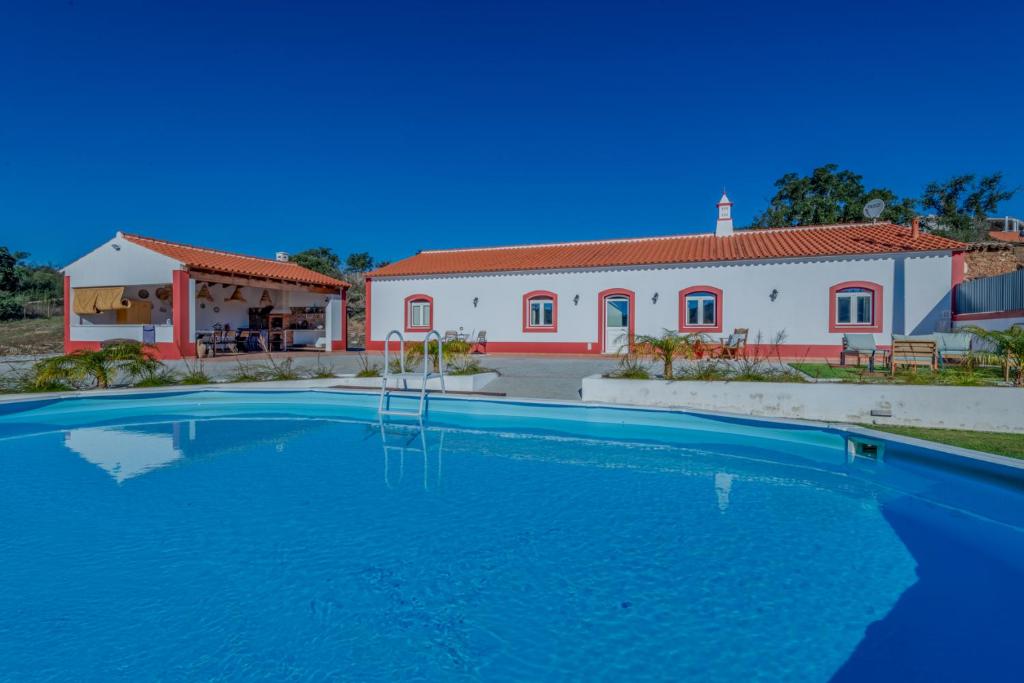 a villa with a swimming pool in front of a house at Casa do Arlindo in São Bartolomeu de Messines