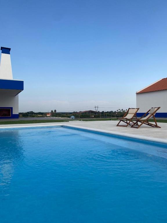 a swimming pool with two chairs next to a building at Serras d'Sal in Alcochete