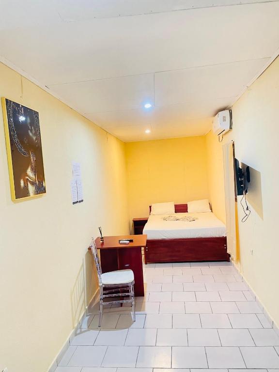 a small room with a bed and a desk at Bulle d'Or Classique in Libreville