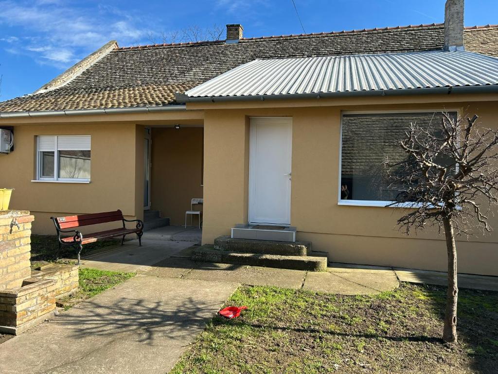 a house with a white door and a bench at Apartmani Centar in Sivac