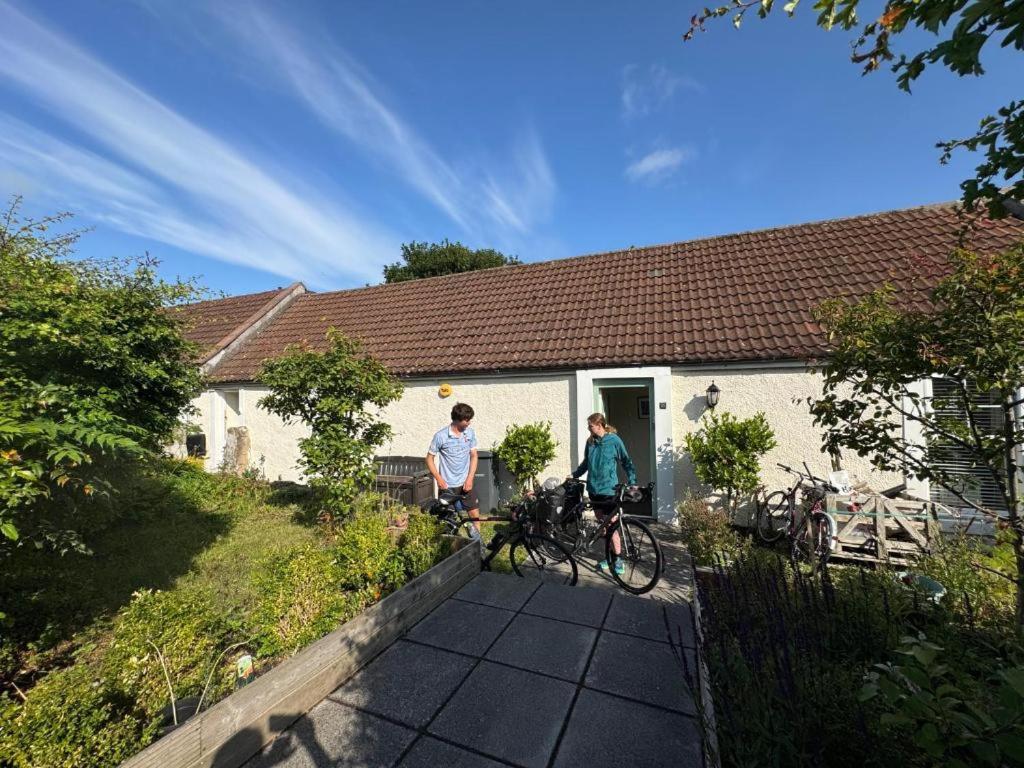 two people on bikes in front of a house at Charming Old Cottage for Share, Cosy Double Room with 2 Single Bed in Edinburgh