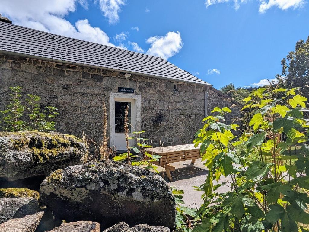 a stone house with a bench and some rocks at L'Ecole Buissonnière de Mazalibrand in Mazet-Saint-Voy