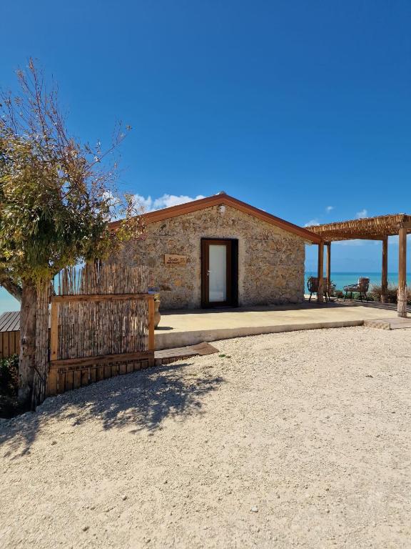 a building on the beach with a fence in front of it at Tendu' Punta Bianca Glamping Camp in Palma di Montechiaro