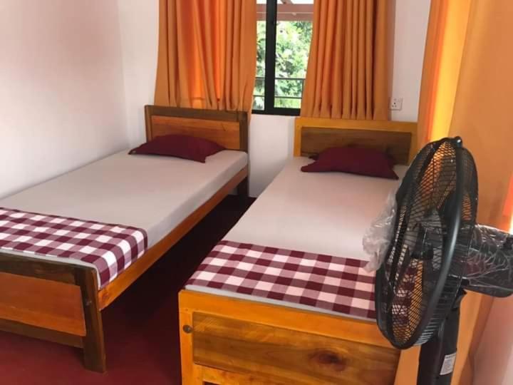 a bedroom with two beds and a window at 5th Dimension Academy rooms in Deniyaya