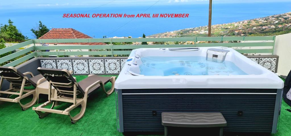 a hot tub sitting on a patio with two chairs at Casa Monte de Paz in Calheta