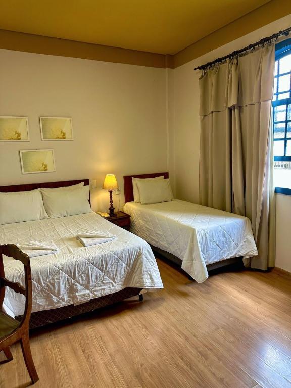 a bedroom with two beds and a window at Hotel Lenheiros in São João del Rei